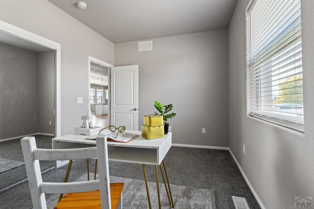 office featuring dark colored carpet, visible vents, and baseboards