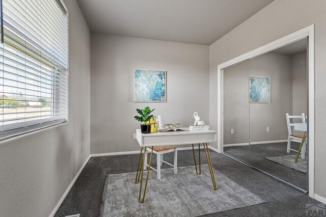 office space featuring baseboards and dark colored carpet