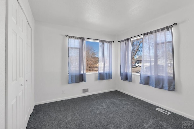 carpeted empty room featuring visible vents and baseboards