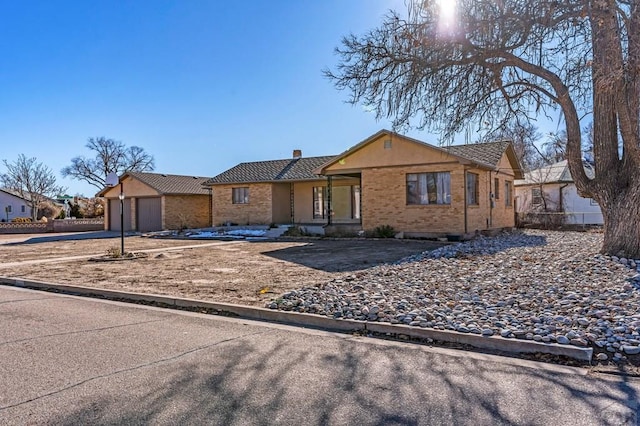 ranch-style home with an attached garage, driveway, a chimney, and brick siding