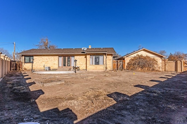 back of house with central AC unit, a patio, a fenced backyard, a gate, and brick siding