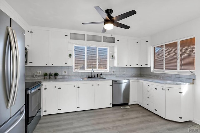 kitchen featuring white cabinetry, stainless steel appliances, a sink, and light countertops