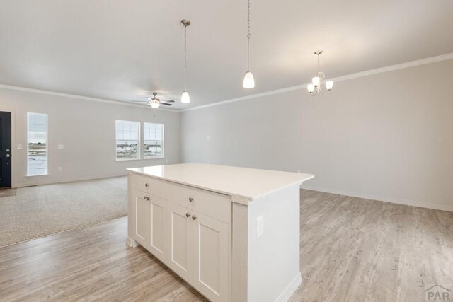 kitchen with a center island, light countertops, hanging light fixtures, open floor plan, and white cabinets