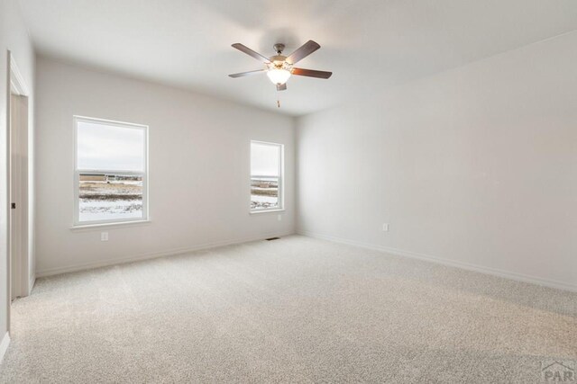 unfurnished room with baseboards, a ceiling fan, and light colored carpet