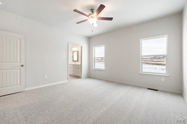 unfurnished bedroom with visible vents, a ceiling fan, light carpet, connected bathroom, and baseboards