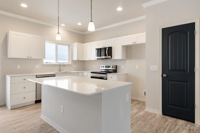 kitchen with white cabinets, a kitchen island, appliances with stainless steel finishes, and light countertops