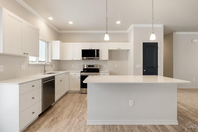 kitchen with appliances with stainless steel finishes, a center island, light countertops, and white cabinetry