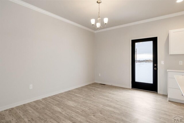 spare room featuring an inviting chandelier, light wood-style flooring, and crown molding