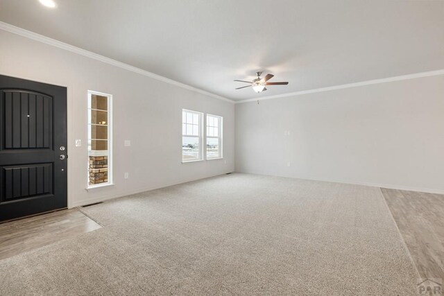 interior space featuring light carpet, baseboards, a ceiling fan, and crown molding