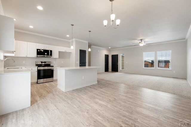 kitchen featuring decorative light fixtures, light countertops, appliances with stainless steel finishes, open floor plan, and a sink