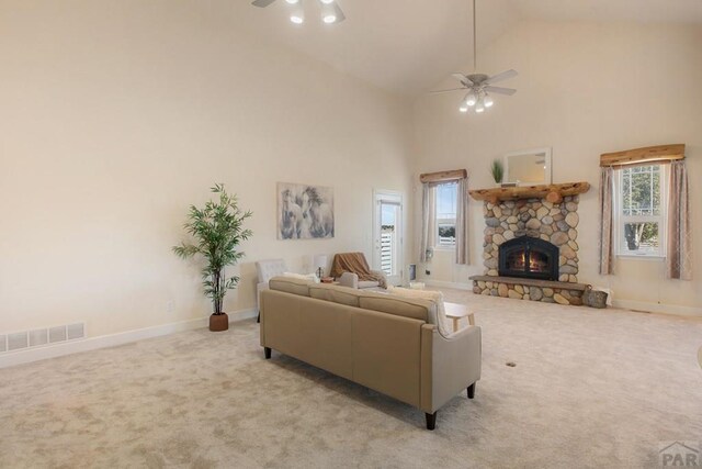 living room with a ceiling fan, a stone fireplace, light colored carpet, and visible vents