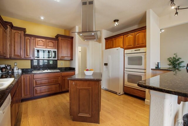 kitchen featuring dark stone countertops, white appliances, a kitchen island, and light wood finished floors