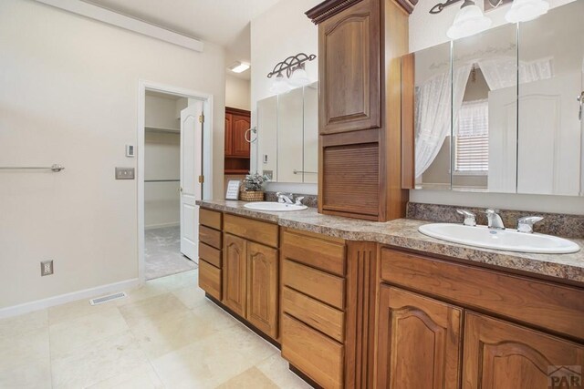 full bath featuring double vanity, baseboards, and a sink