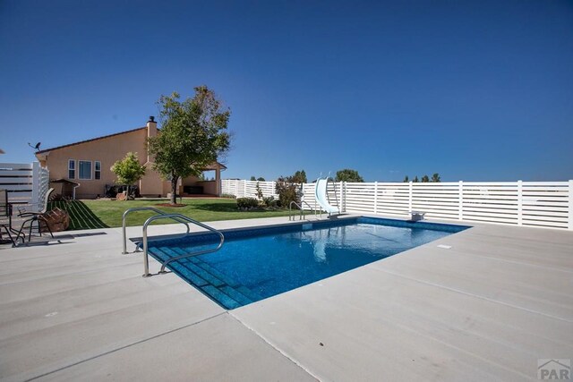 view of pool featuring a fenced in pool, a lawn, a patio area, fence, and a water slide