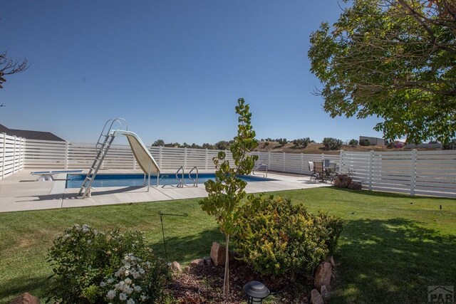 view of pool with a patio area, a fenced backyard, a lawn, and a water slide