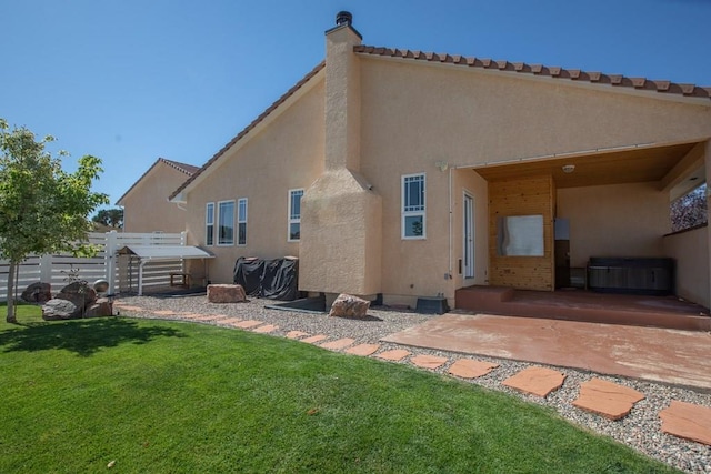 rear view of house with a patio, a chimney, a yard, stucco siding, and fence