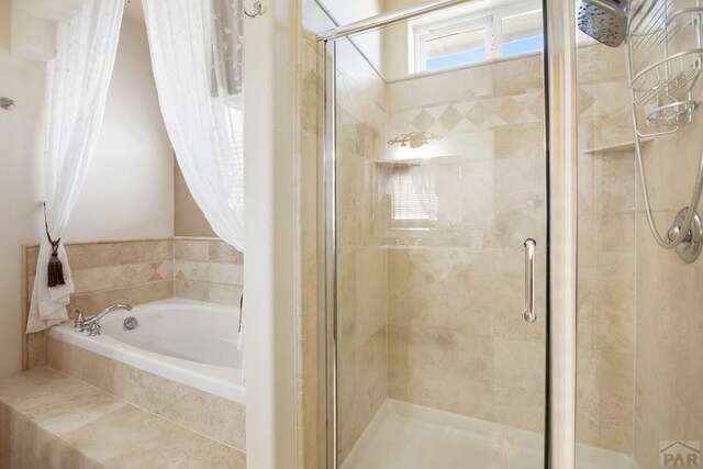 bathroom featuring a stall shower and a bath