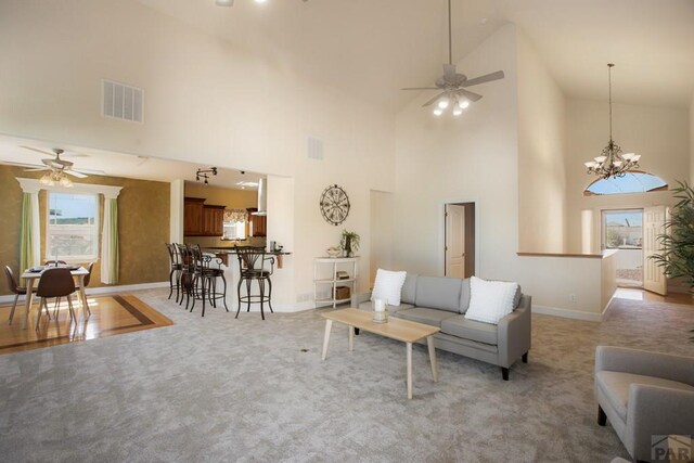 living room featuring visible vents, light carpet, baseboards, and ceiling fan with notable chandelier