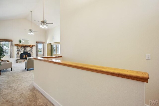 corridor featuring light carpet, high vaulted ceiling, and baseboards