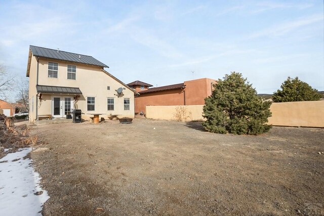 back of house with a standing seam roof, fence, and metal roof