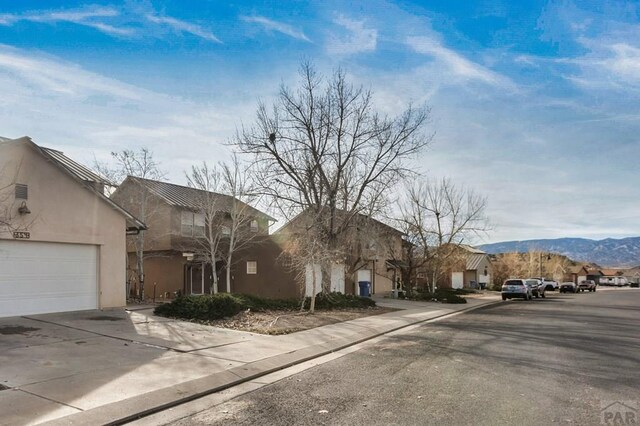 view of street with sidewalks, a residential view, a mountain view, and curbs