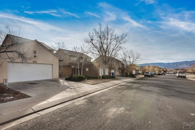 view of road with curbs, a residential view, a mountain view, and sidewalks