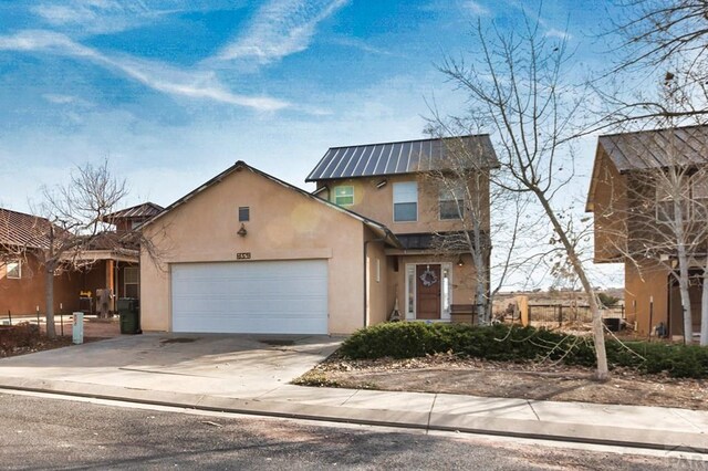 traditional-style home with an attached garage, metal roof, concrete driveway, and stucco siding