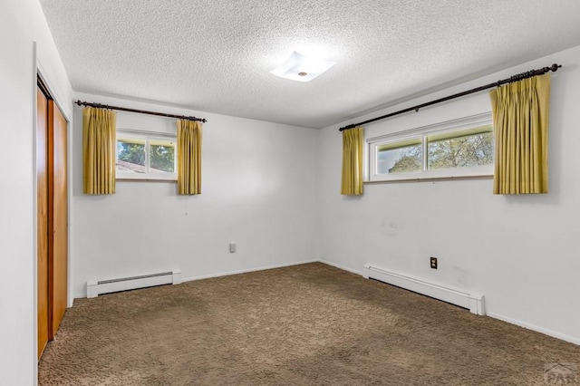 empty room featuring a baseboard heating unit, a textured ceiling, and carpet