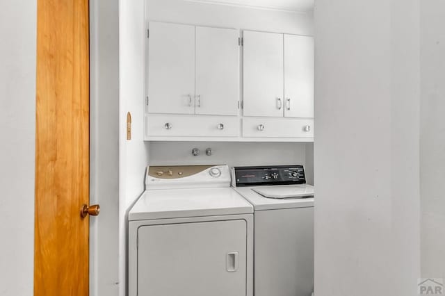 laundry room with washing machine and clothes dryer and cabinet space