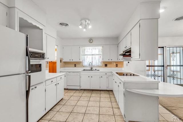 kitchen with light countertops, white appliances, a sink, and white cabinets