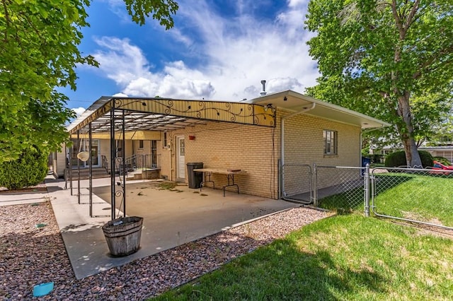 back of property with a patio, a gate, fence, a yard, and brick siding