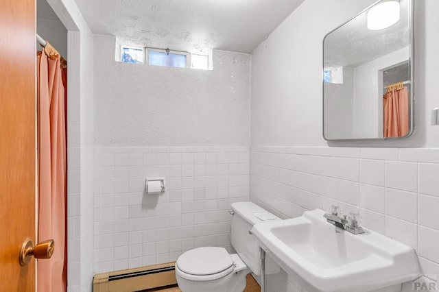 bathroom featuring toilet, a wainscoted wall, a baseboard radiator, a sink, and tile walls