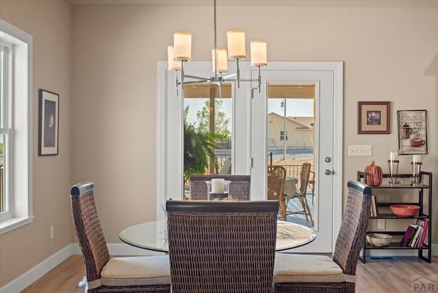 dining area with light wood-style floors, baseboards, and a notable chandelier