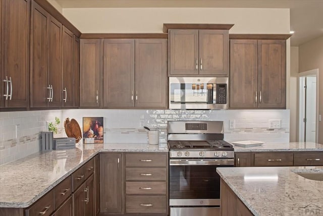 kitchen featuring tasteful backsplash, appliances with stainless steel finishes, and light stone countertops