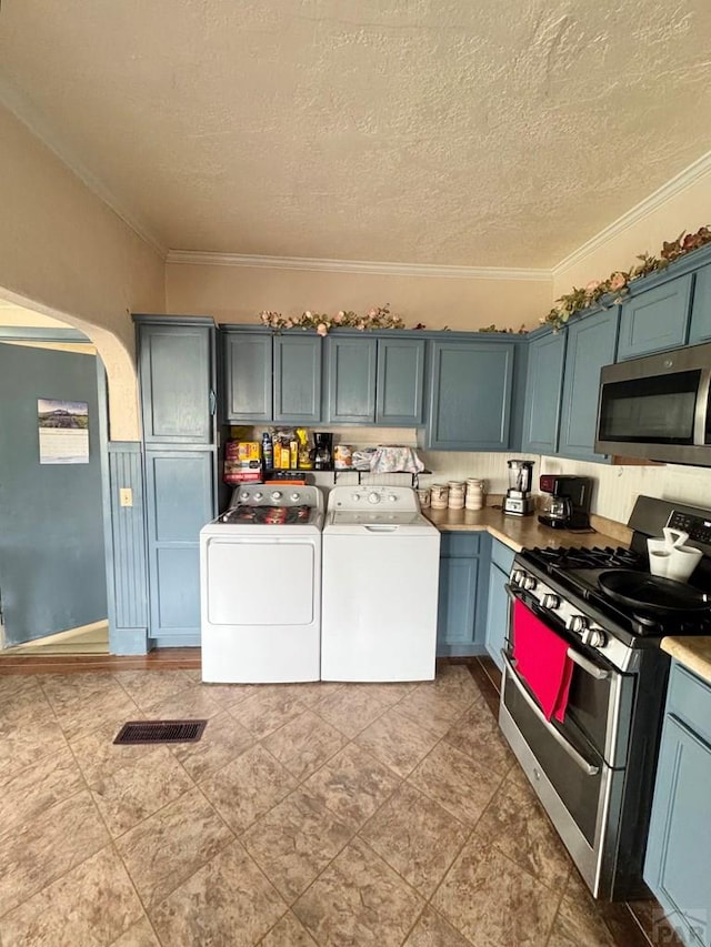318 W 10th St, La Junta, CO 81050 - kitchen with stainless steel appliances, arched walkways, washing machine and clothes dryer, ornamental molding, and a textured ceiling
