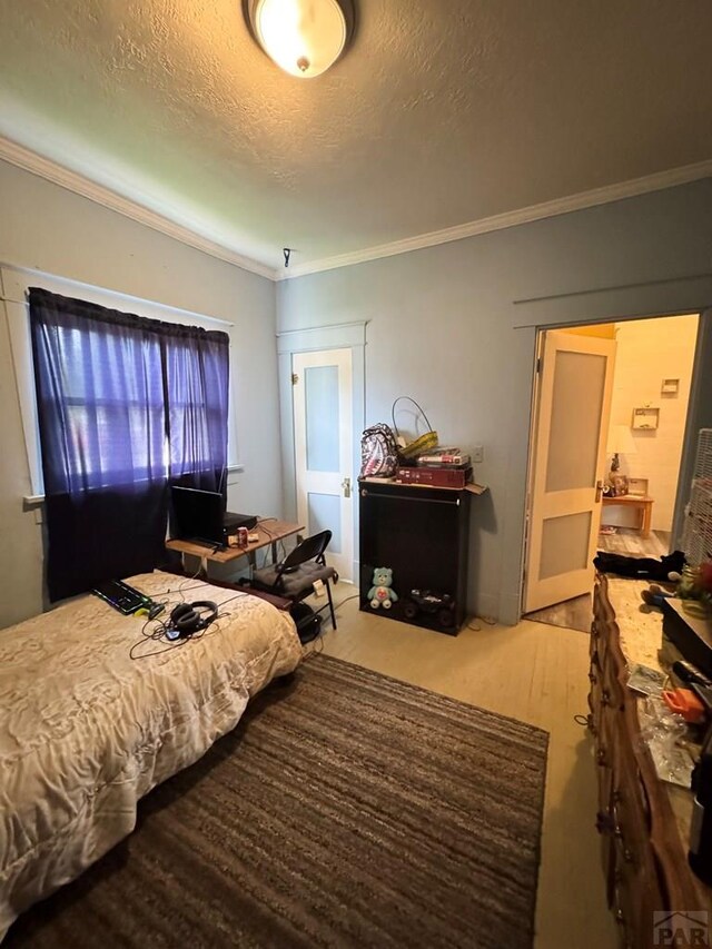 318 W 10th St, La Junta, CO 81050 - bedroom with a textured ceiling, crown molding, and wood finished floors