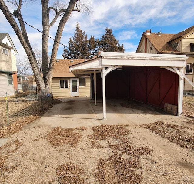 back of property featuring concrete driveway and fence