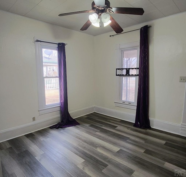 spare room featuring a ceiling fan, dark wood-style flooring, and baseboards