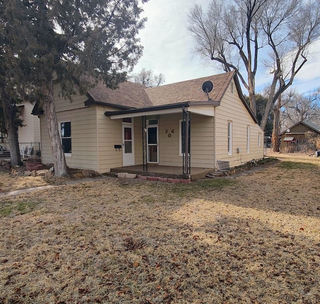 view of front of property featuring a shingled roof and a front lawn