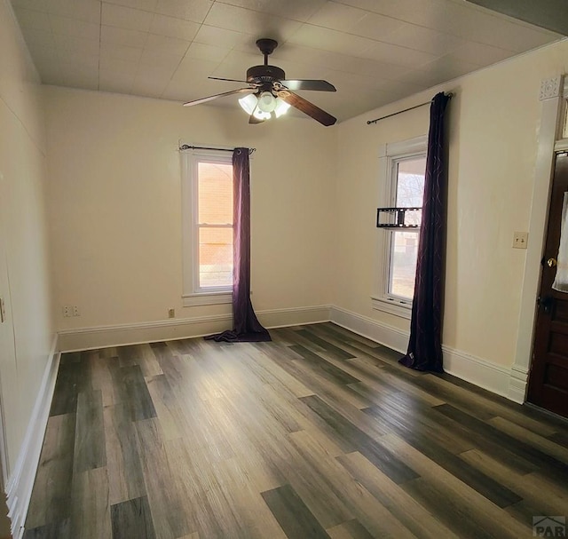 empty room featuring dark wood-type flooring, a healthy amount of sunlight, and baseboards