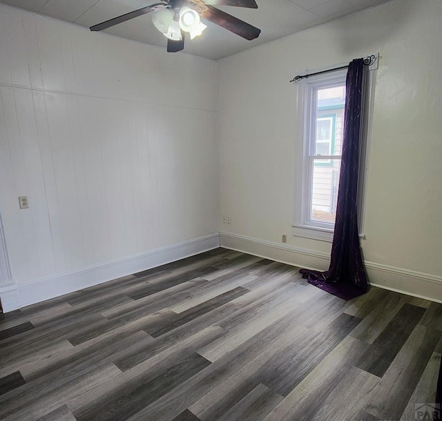 spare room with ceiling fan, dark wood-type flooring, and baseboards