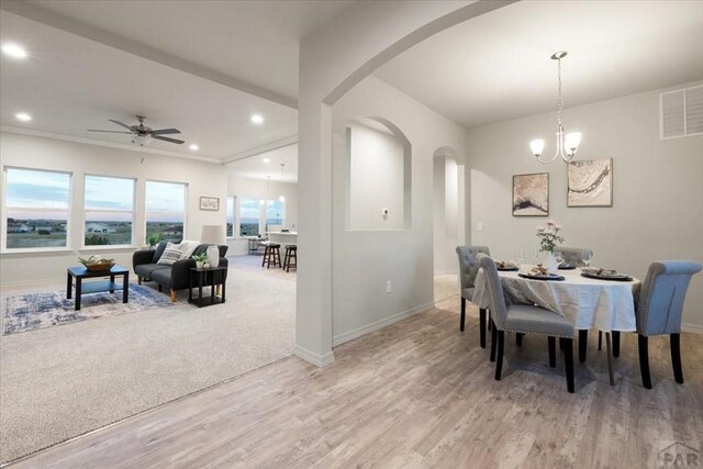 dining area with light wood-type flooring, baseboards, visible vents, and arched walkways