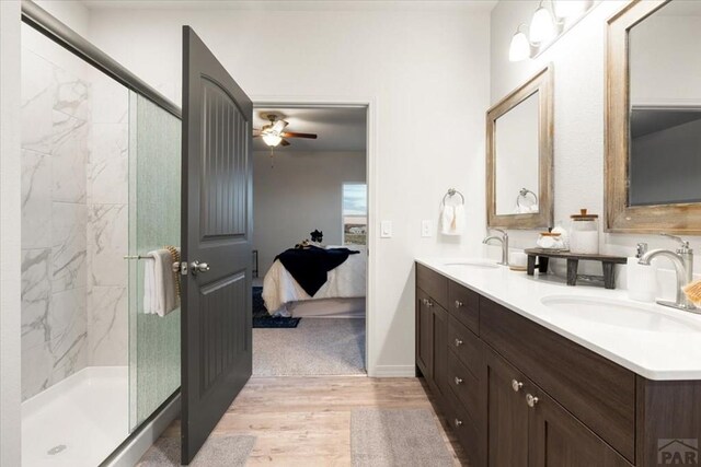 ensuite bathroom featuring a marble finish shower, connected bathroom, a sink, and wood finished floors