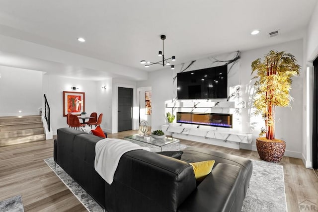 living room featuring a high end fireplace, baseboards, stairway, light wood-style flooring, and recessed lighting