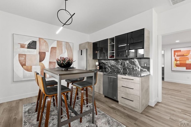 kitchen with backsplash, dishwasher, light wood-style flooring, dark cabinetry, and open shelves