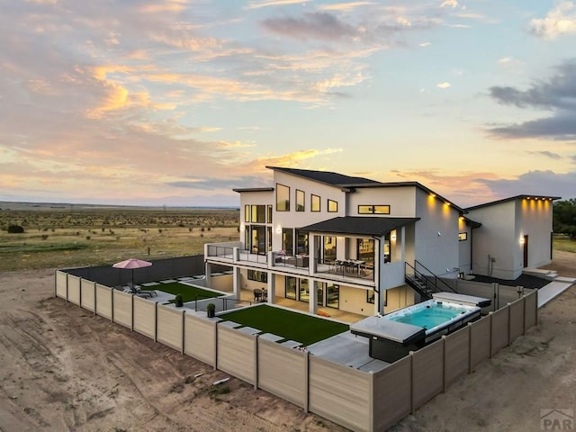 back of property featuring a patio, a fenced backyard, stucco siding, stairs, and an outdoor hot tub