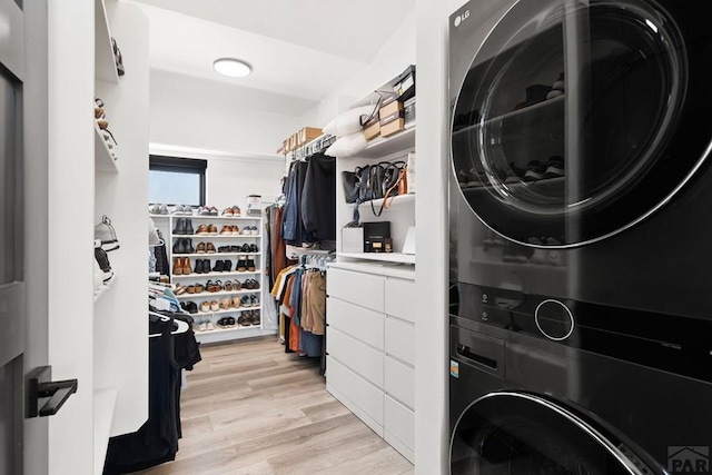 laundry room with light wood finished floors, laundry area, and stacked washer and clothes dryer