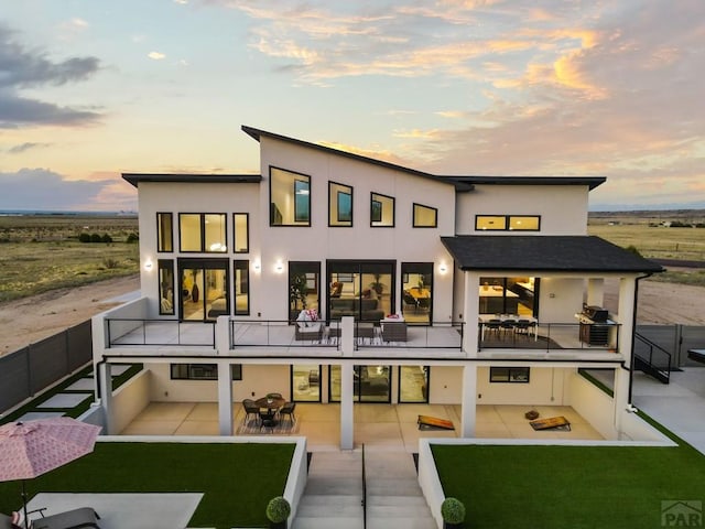 back of house featuring an outdoor living space, stucco siding, a patio, and a balcony