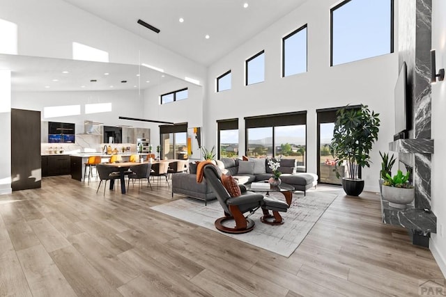 living area with plenty of natural light, recessed lighting, light wood-style floors, and a premium fireplace