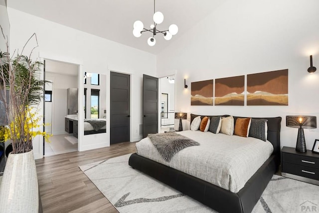 bedroom featuring an inviting chandelier, light wood-type flooring, and high vaulted ceiling